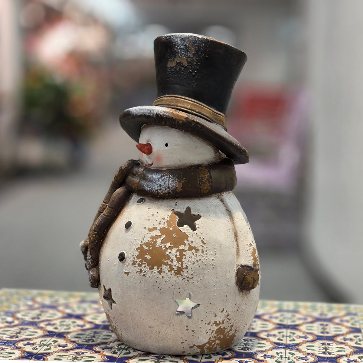 Distressed snowman candleholder with black top hat, front three-quarter view