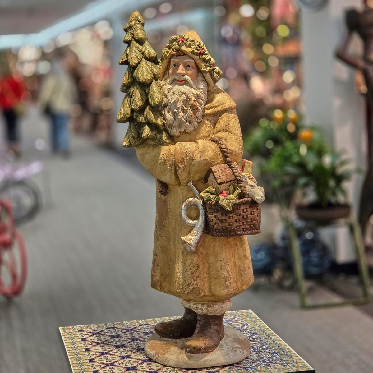 Full Santa figurine with evergreen tree and basket, shown from the front in a shop