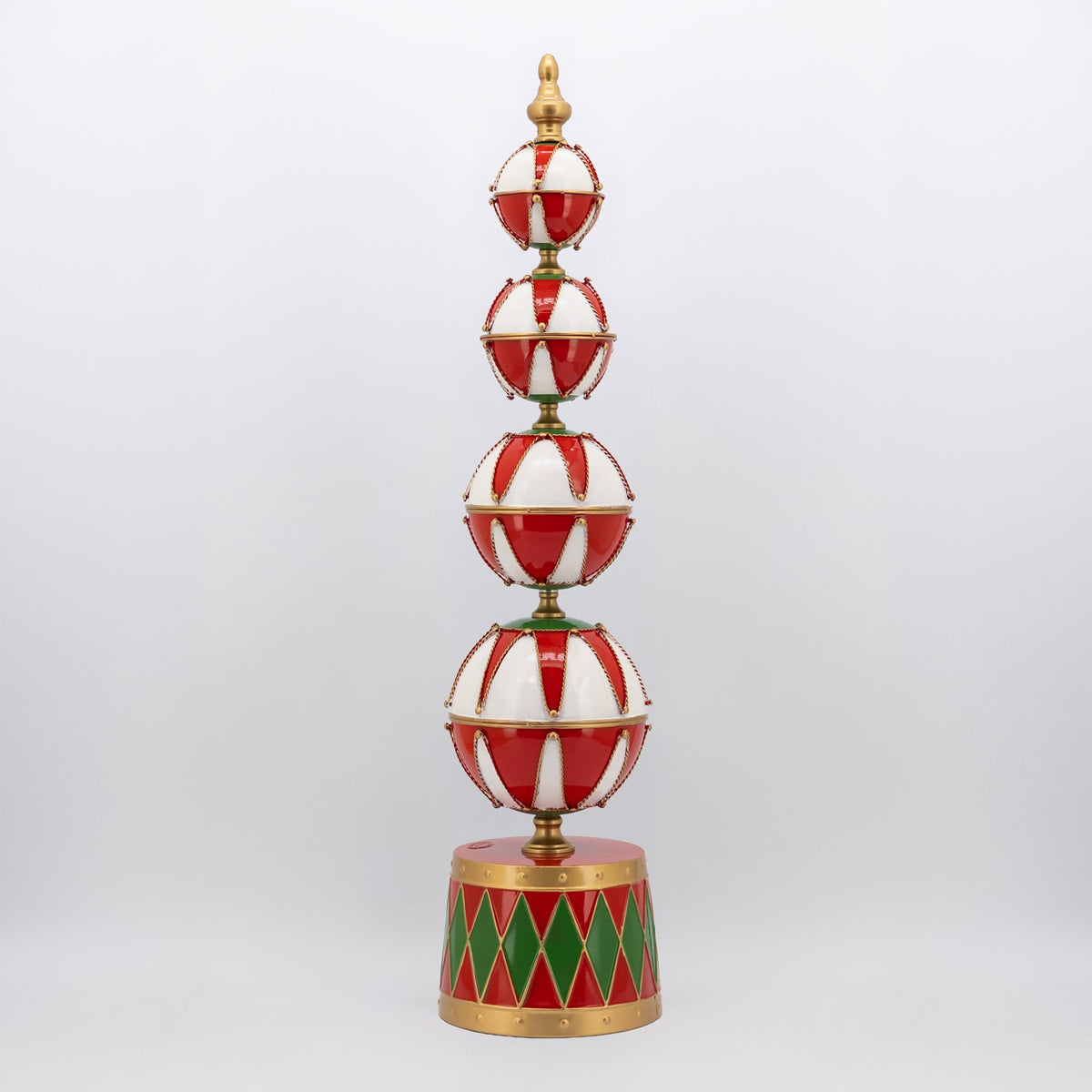 A tall tiered ornament tower with red and white baubles above a red and green diamond-patterned base.