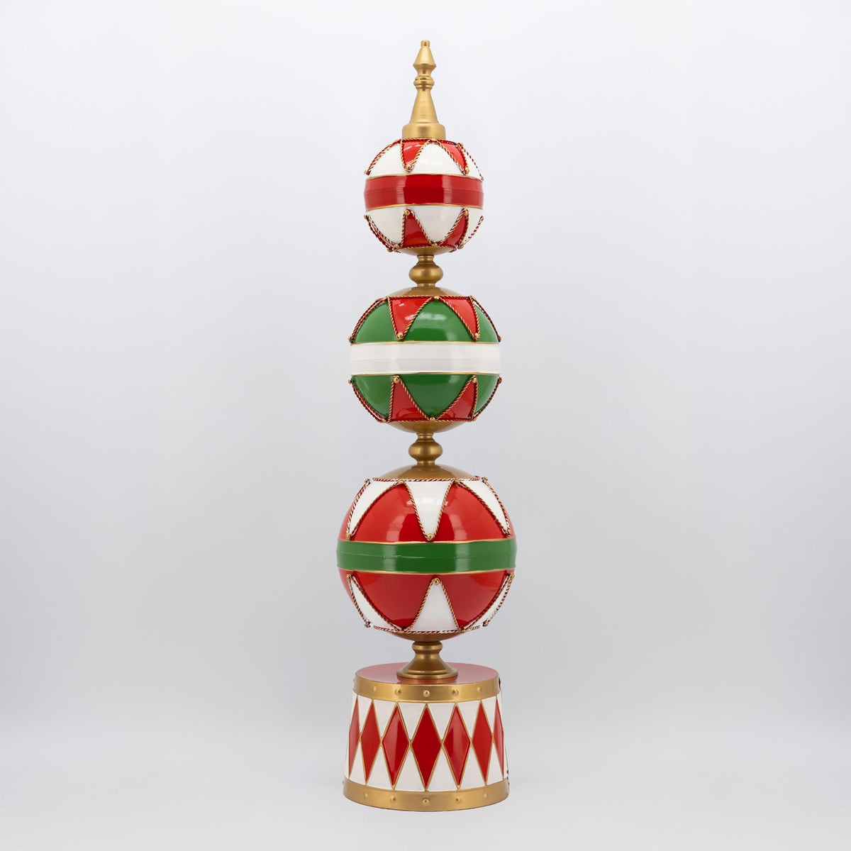 Tall decorative tower of three red, green, and white patterned spheres on a drum-shaped base.