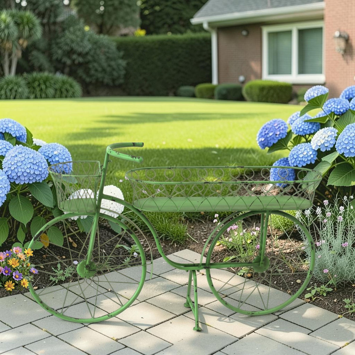 Green metal bicycle planter with two wire baskets displayed among flowers on a garden patio.