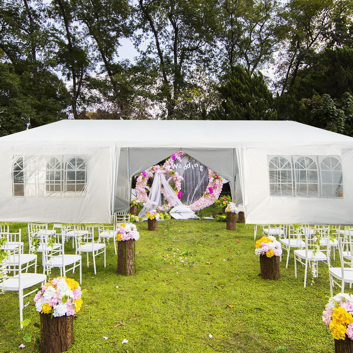 White canopy tent with a flower-decorated open entrance, clear window panels, and white chairs arranged on grass.