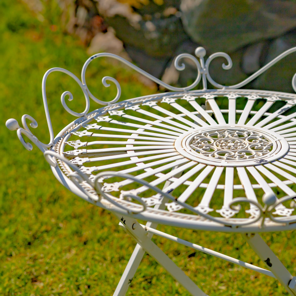 Close view of the white table’s radial metalwork center and curled decorative rim.