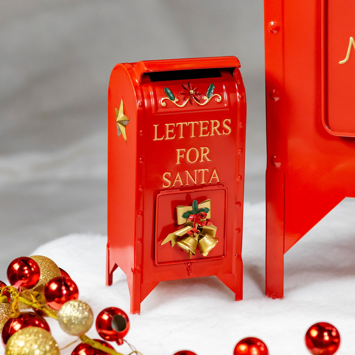 Close view of a small glossy red mailbox with gold lettering and bell decoration