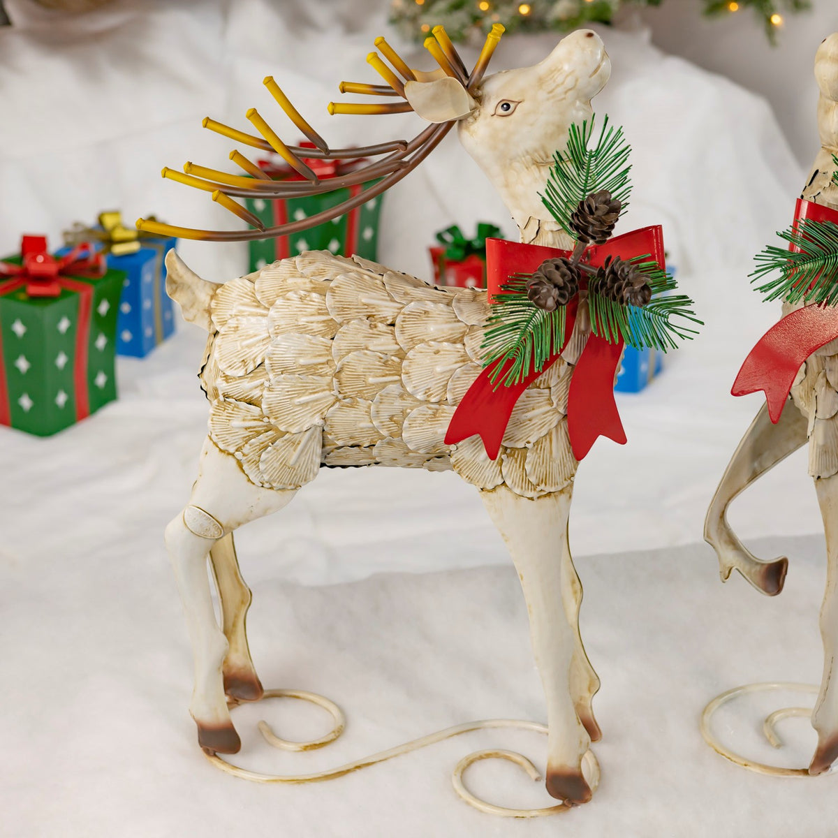 Cream iron reindeer with a red bow and pinecone accents, shown from the side