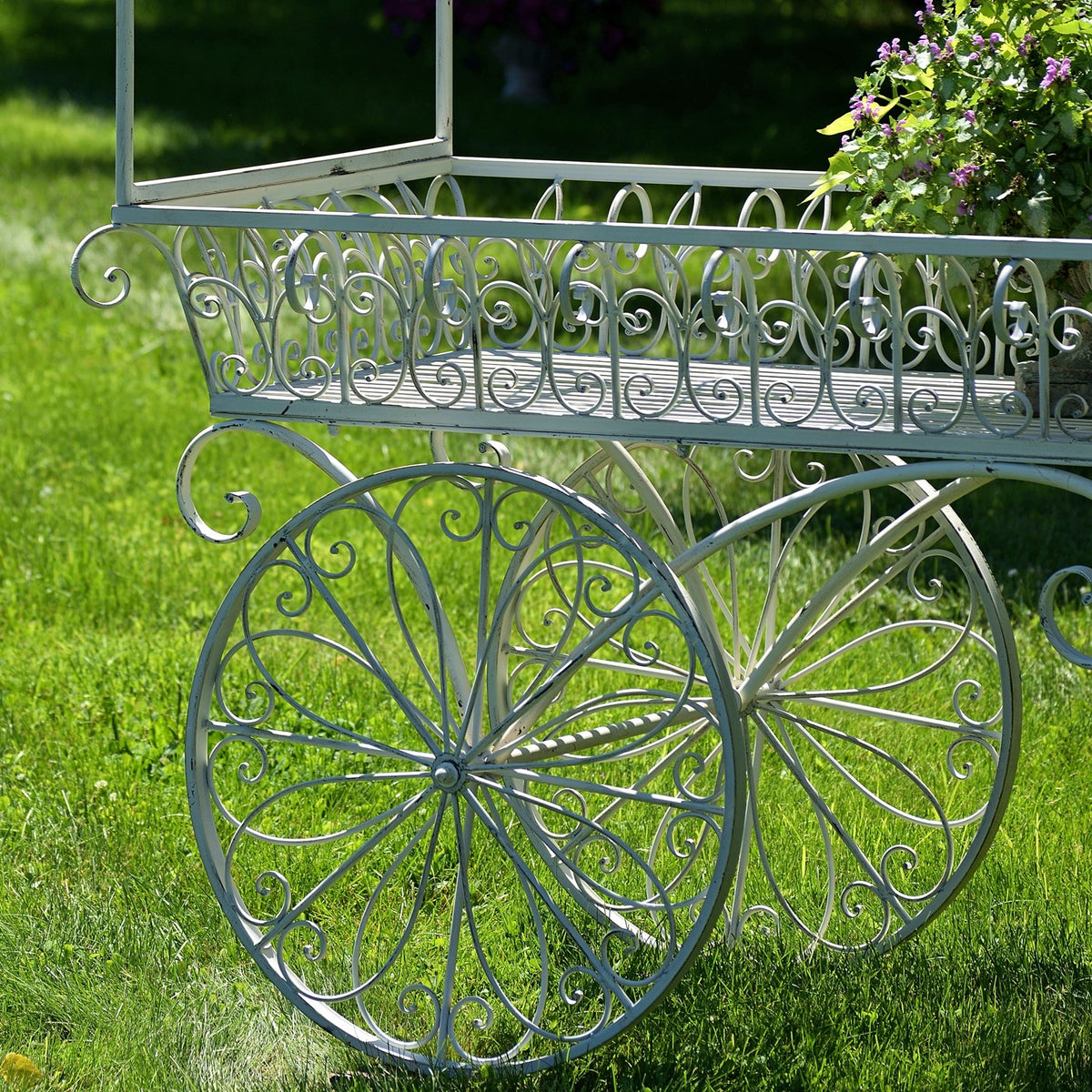 Close view of the cart’s decorative spoked wheels and curled metal basket railing.