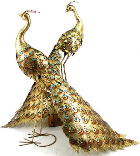 Two gold peacock sculptures with blue-green jeweled tails on a white background