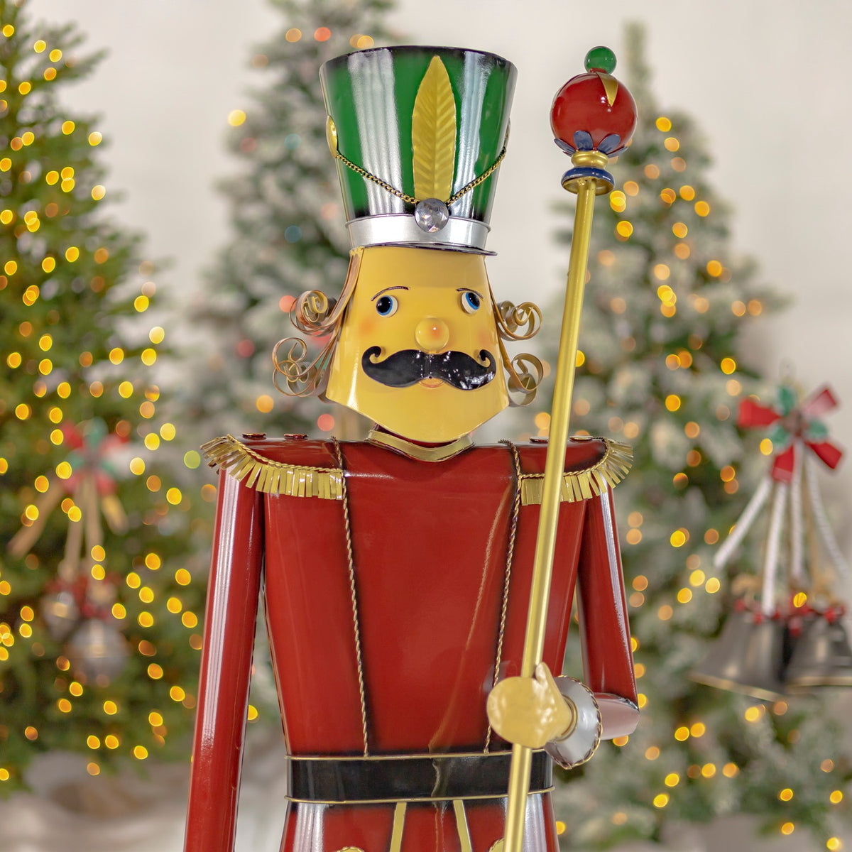Close view of the nutcracker's face, upper body and baton against a festive tree