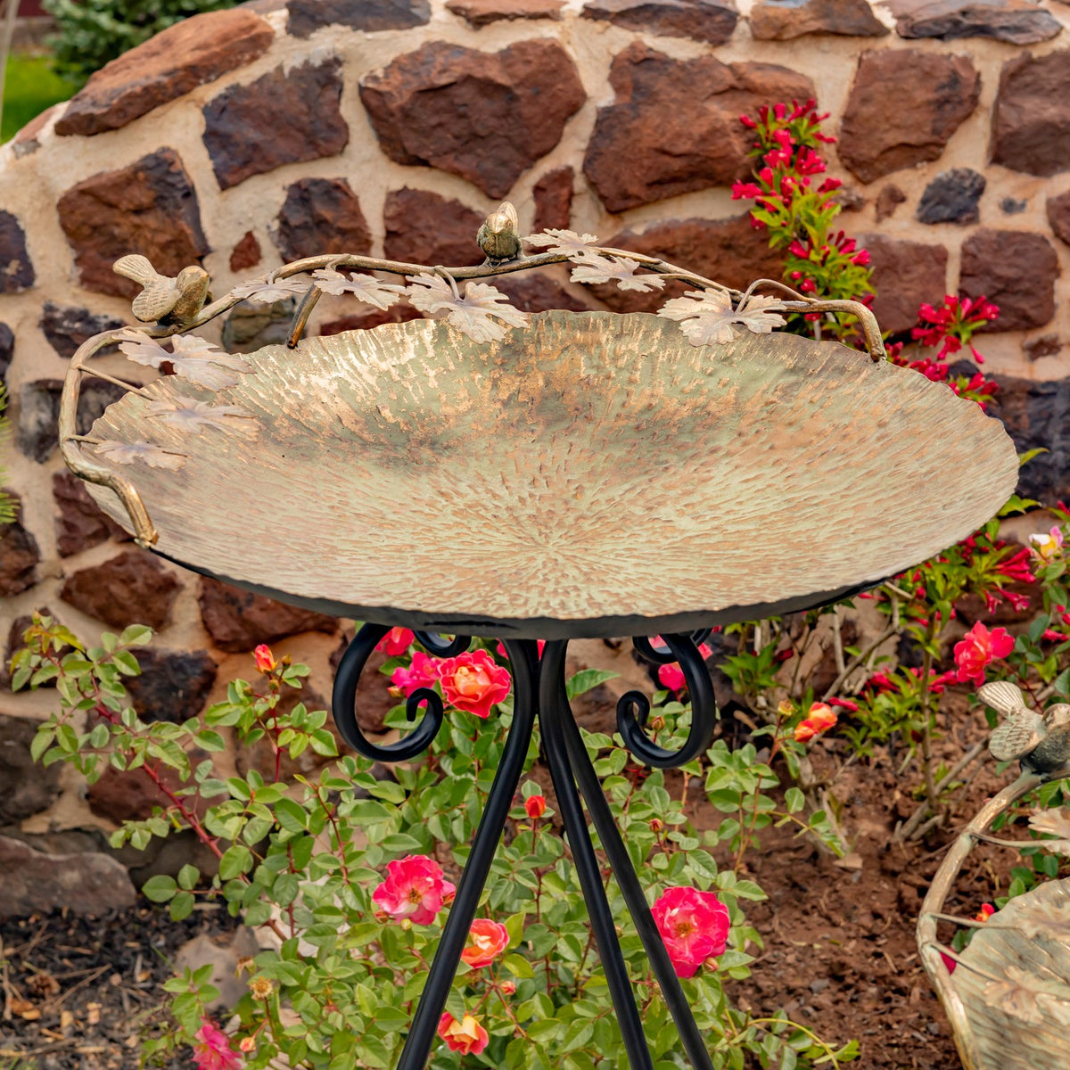 A textured gold-toned birdbath bowl with small bird ornaments along its rim.