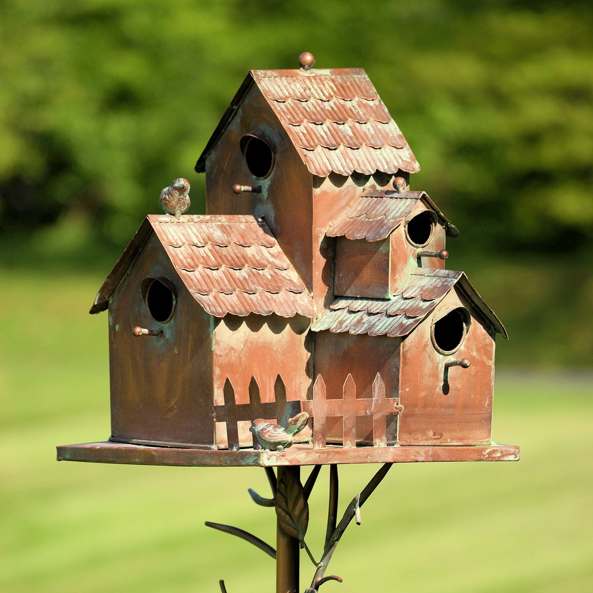Antique copper multi-house birdhouse stake shown against a bright green lawn