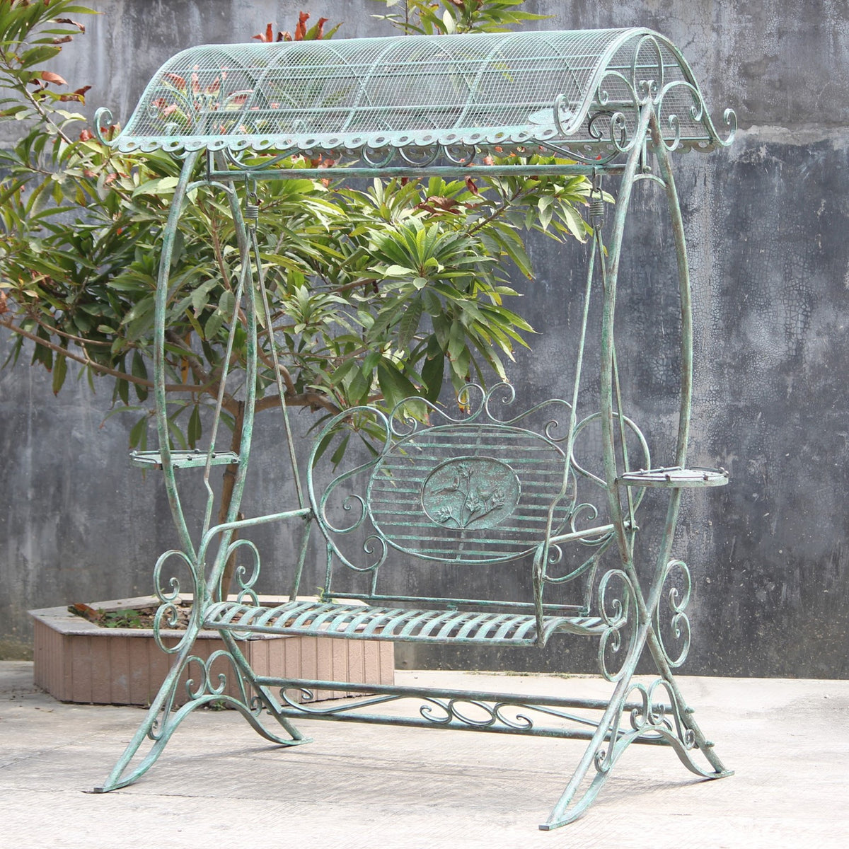 A garden swing bench with an arched mesh canopy and ornate frame stands beside a planter.