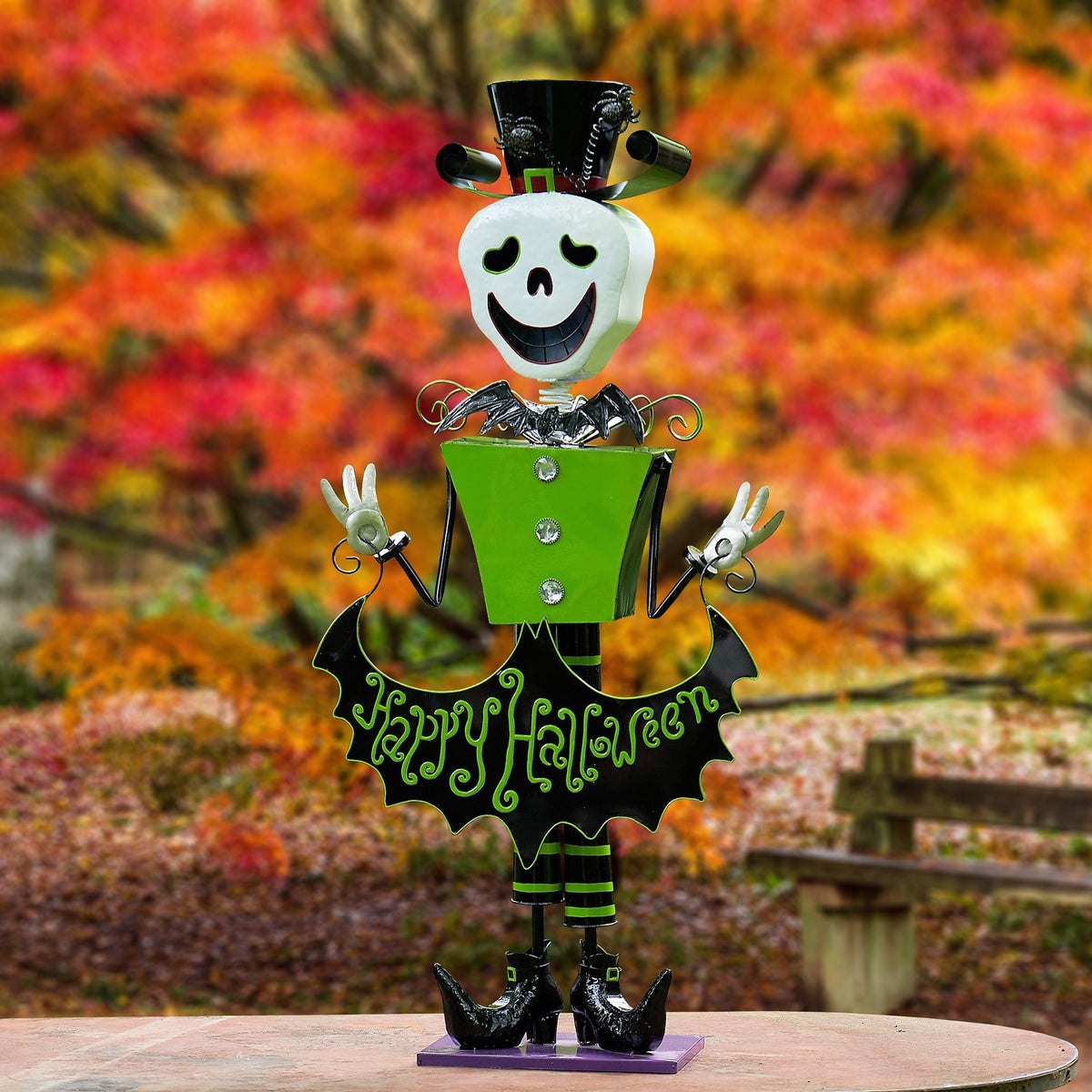 Front-facing skeleton figurine raises both hands, with a bat-shaped sign across its green outfit.
