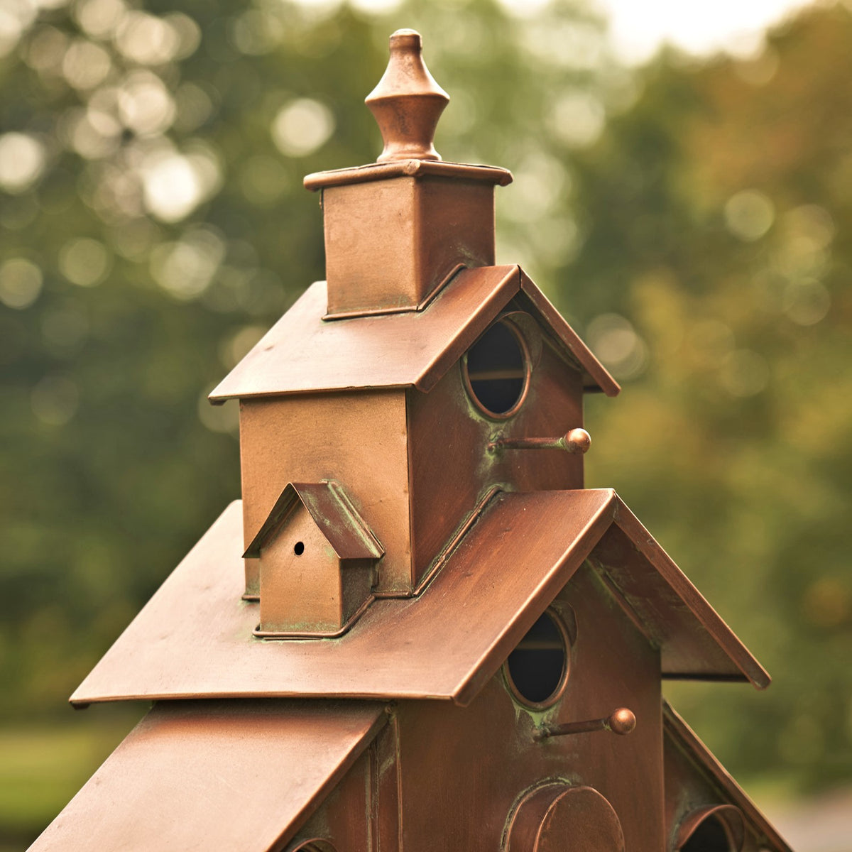 Close-up of the birdhouse’s upper tiers, showing small entry holes, projecting roofs, and a finial.