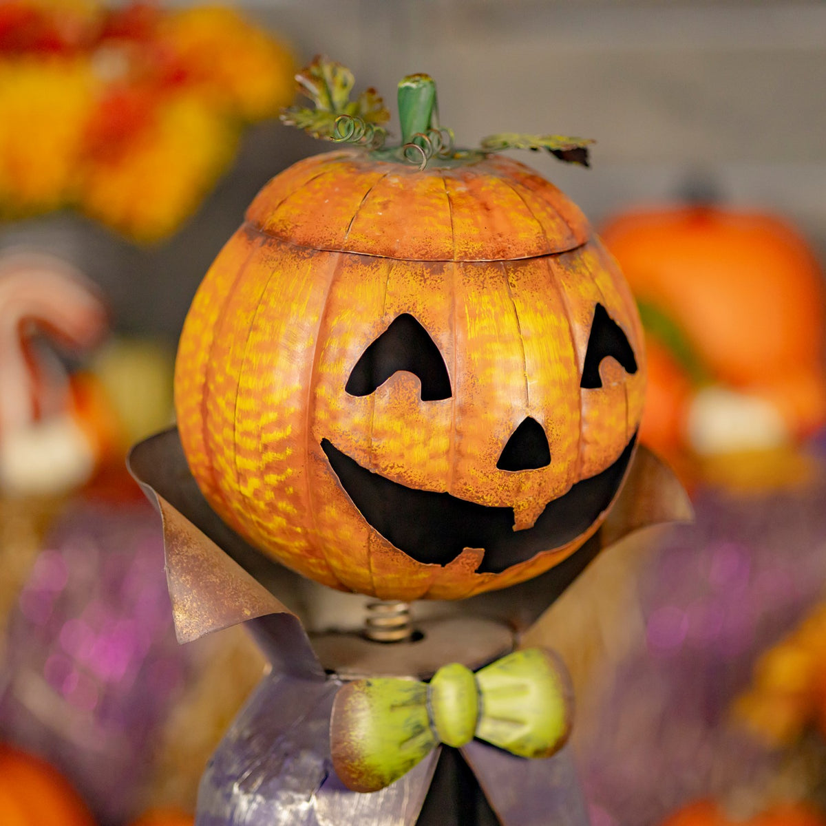 Close view of the orange pumpkin head and green bow on the figurine
