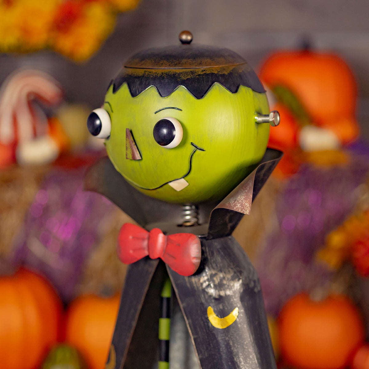 Angled close-up of the green monster head, red bow tie, and dark cape