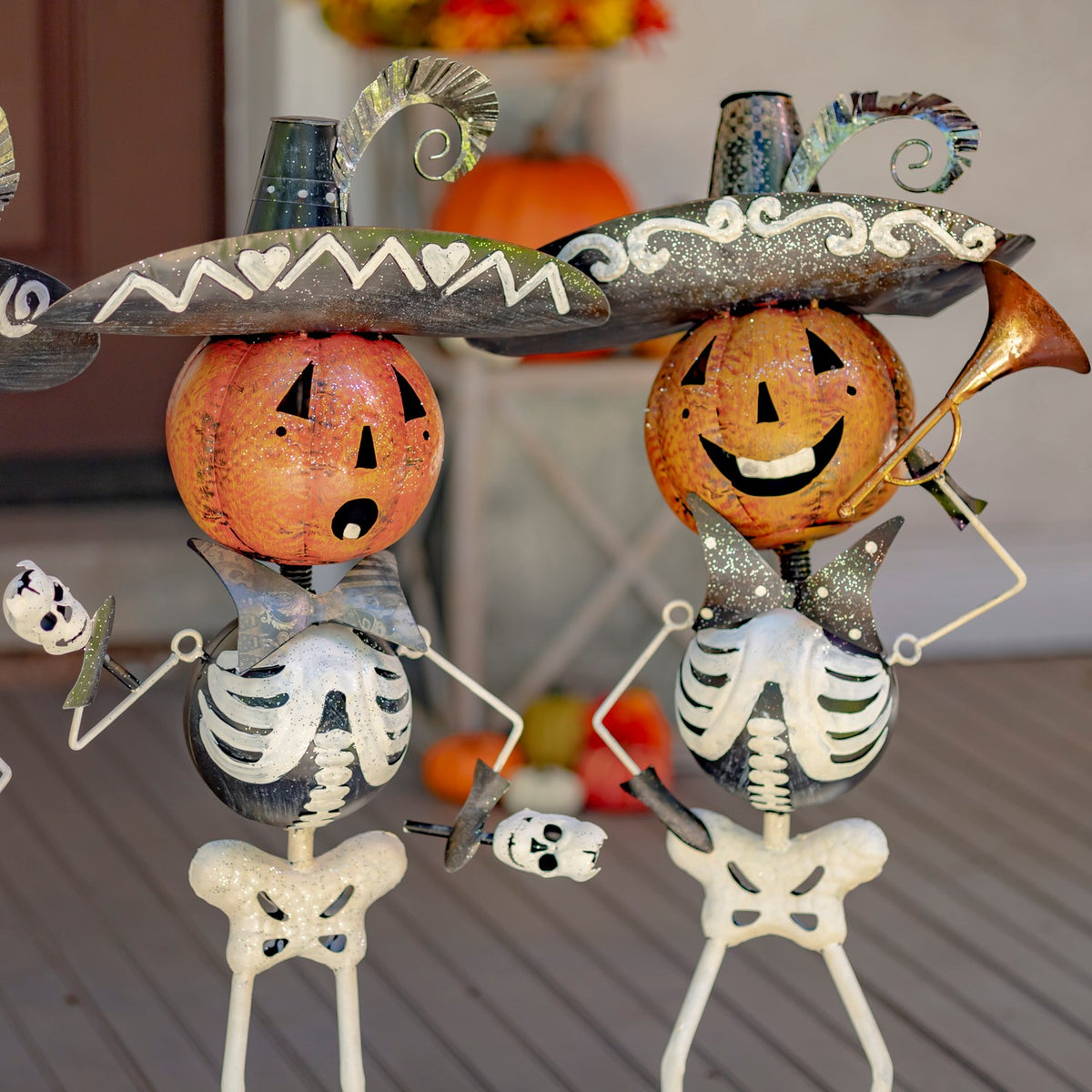 Close view of two iron skeleton musicians with pumpkin heads and instruments