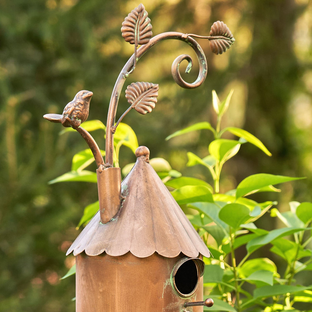 Close view of the copper birdhouse roof, entry hole, bird sculpture, and curled leaf details