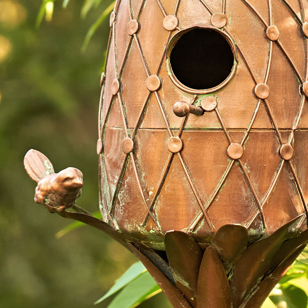 Close-up of the copper-tone birdhouse entry hole and small bird perch