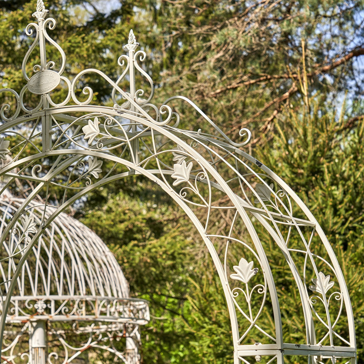 Close view of the arch’s curved metalwork, floral motifs and decorative finials.