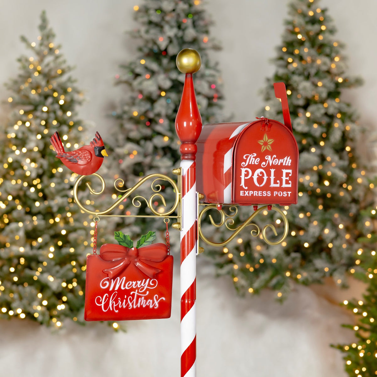 Closer view of the red mailbox, gold scrollwork, cardinal ornament, and hanging Merry Christmas sign.