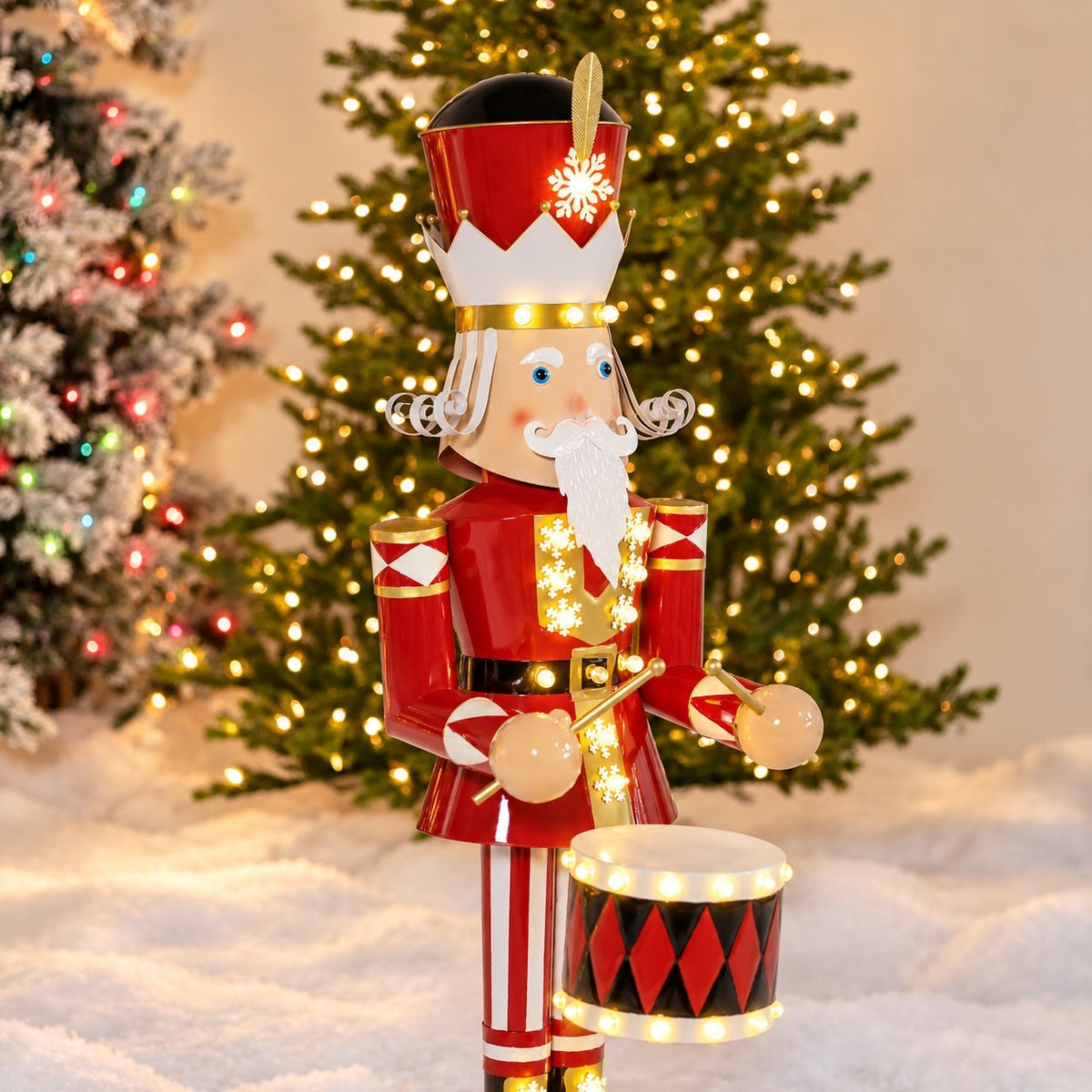 Angled view of the nutcracker holding drumsticks beside its illuminated drum, with a Christmas tree behind it.