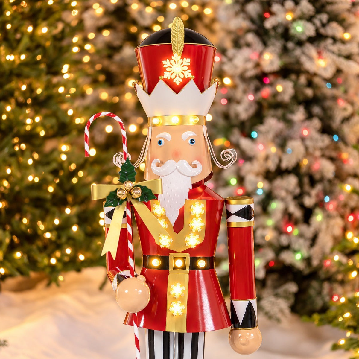 Closer view of the nutcracker’s crown, face, illuminated red coat, and candy cane staff.