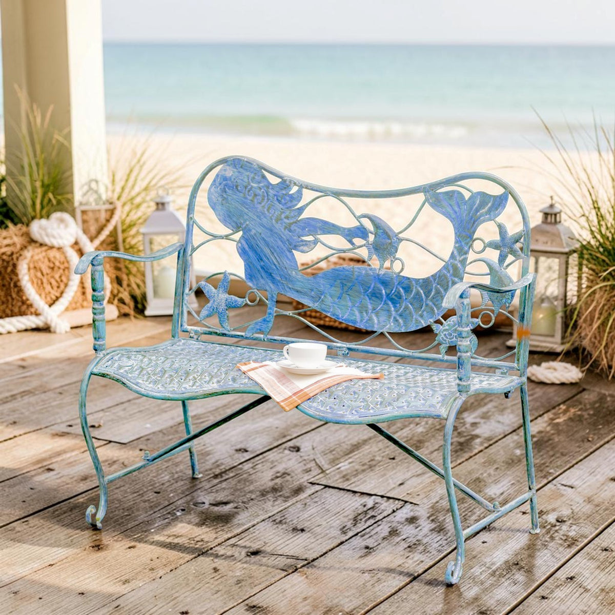 Front view of a blue mermaid bench on a beachside deck, showing its curved seat and ornate back.