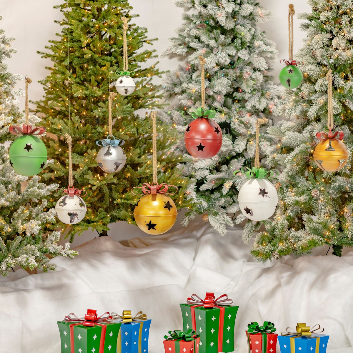 Assorted colorful hanging bells displayed among decorated Christmas trees