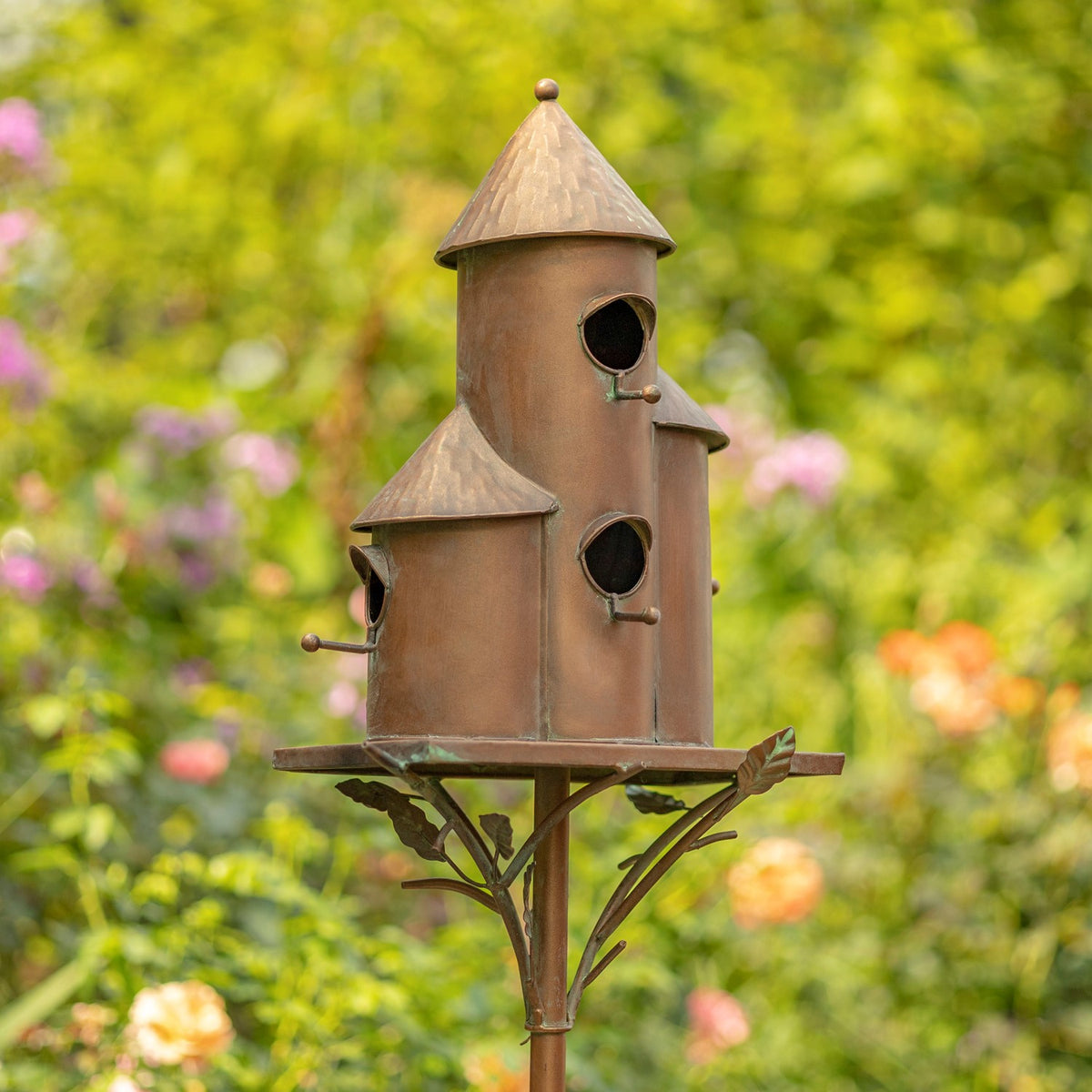 Antique copper triple birdhouse stake from a side angle outdoors