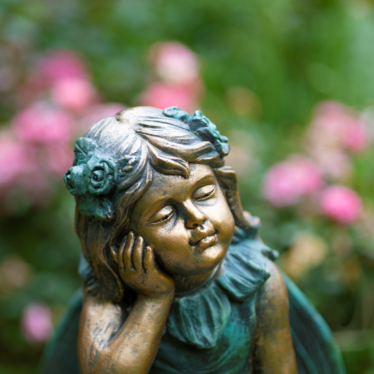 Close-up of the fairy’s serene face, wavy hair, and flower adornments against a blurred garden.