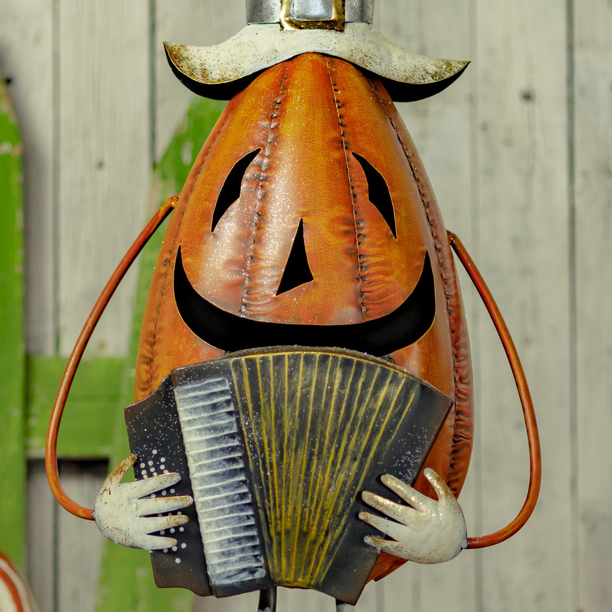Close-up of the orange pumpkin figurine's face, hat brim and accordion