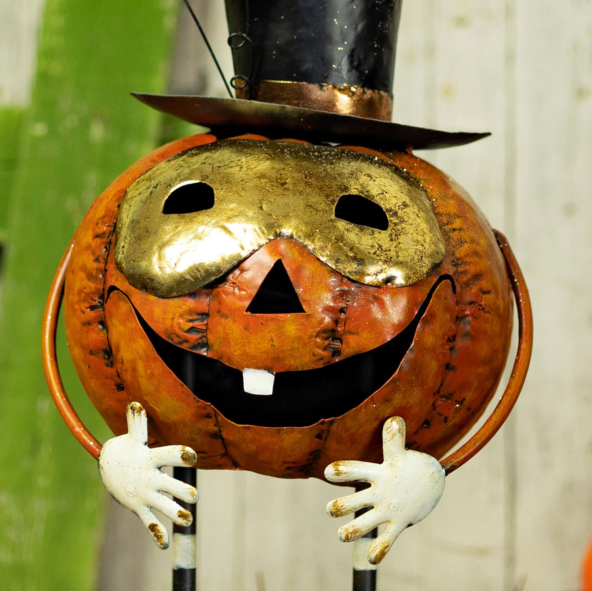 Close front view of the orange pumpkin figurine with gold detailing and a black smile