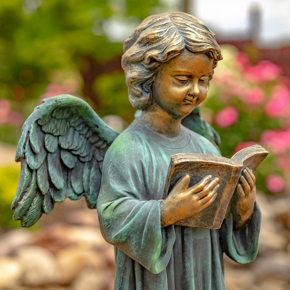 Close view of a winged angel looking down as it holds an open book.