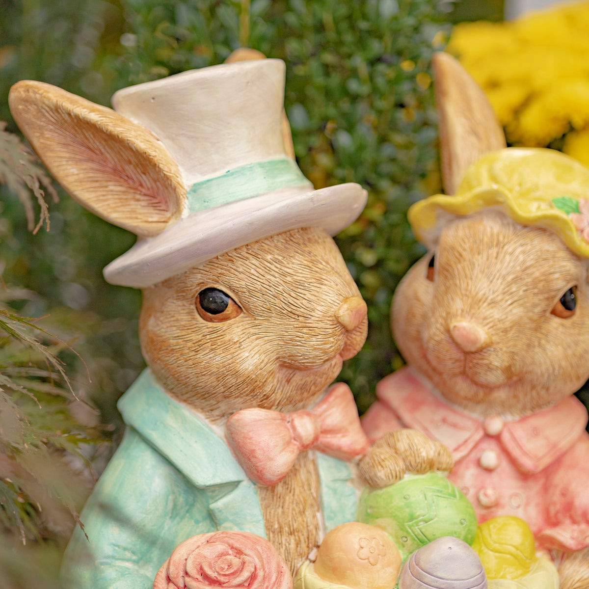 Close view of the rabbits’ faces, hats, clothing, and the decorated eggs in their basket.