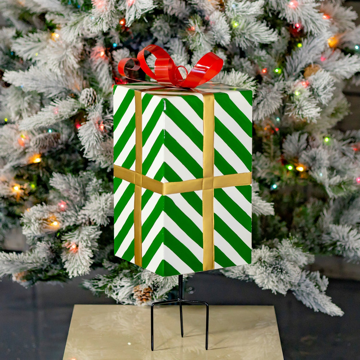 Closer view of the striped gift box and gold-colored bands, with its black stake visible below.