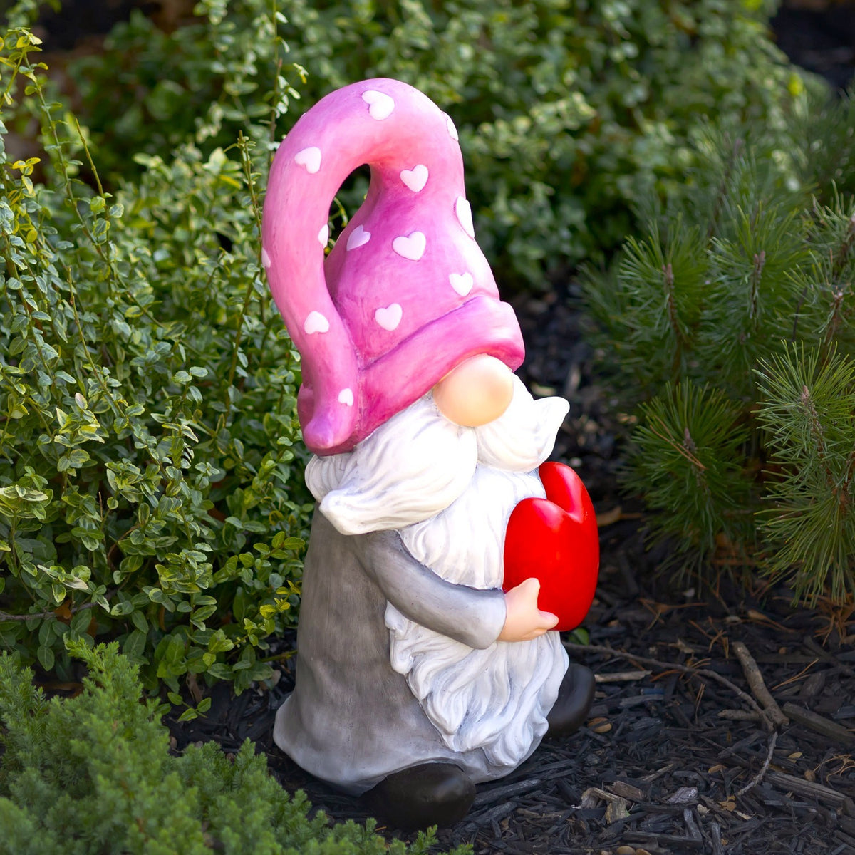Side view of a heart-holding gnome displayed among outdoor greenery