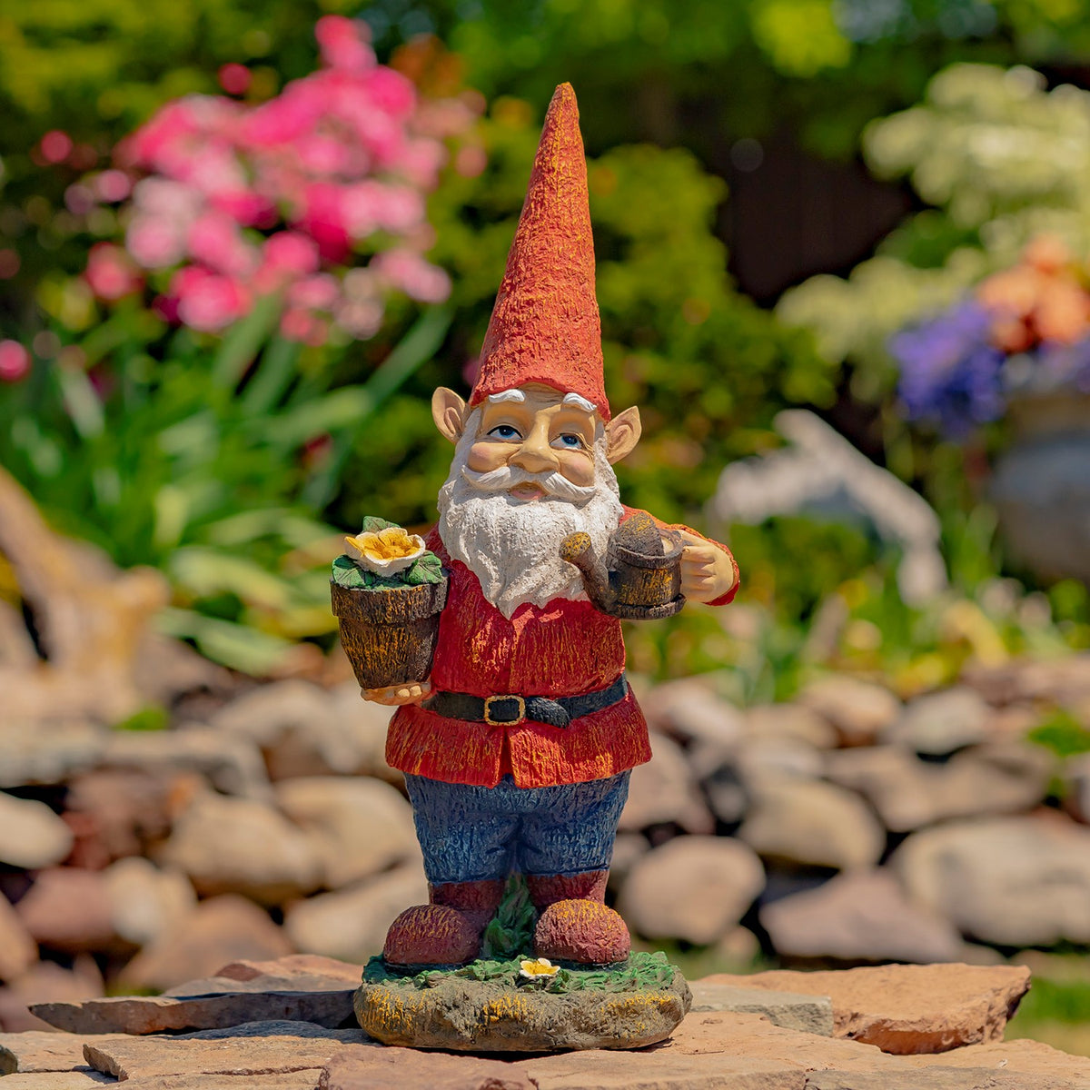 Full gnome statue stands on a leafy base among garden stones and flowers.