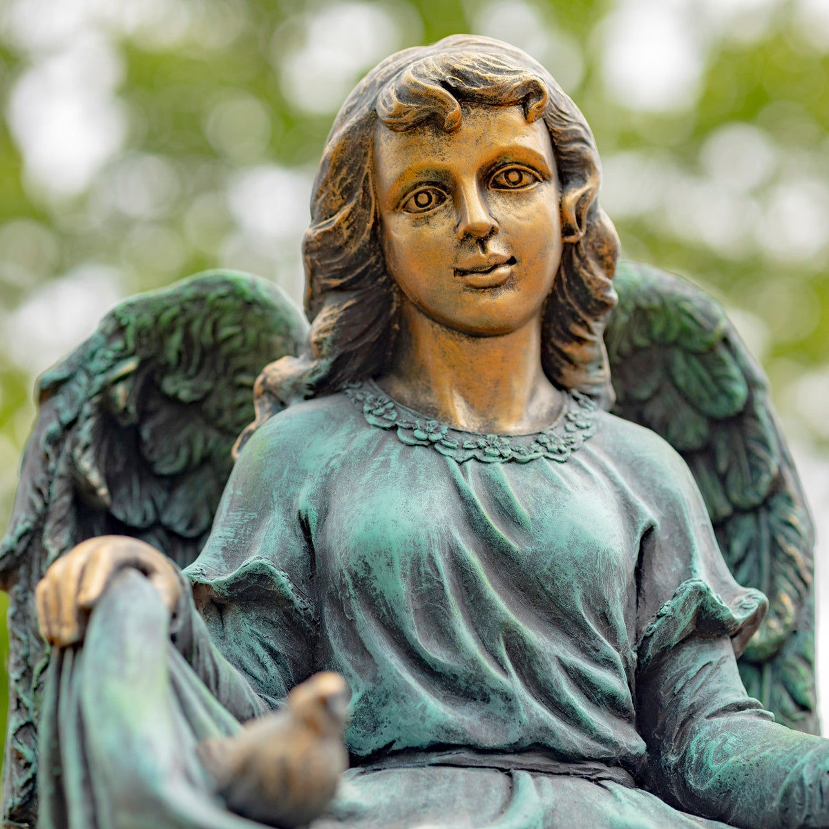 Close view of the angel’s face, feathered wings, and a small bird resting in the fabric.