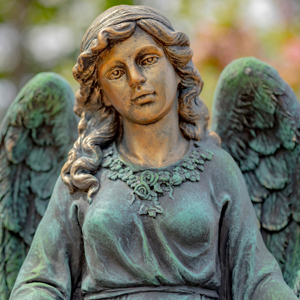 Close-up of the angel’s face, curled hair, necklace, and textured wings.