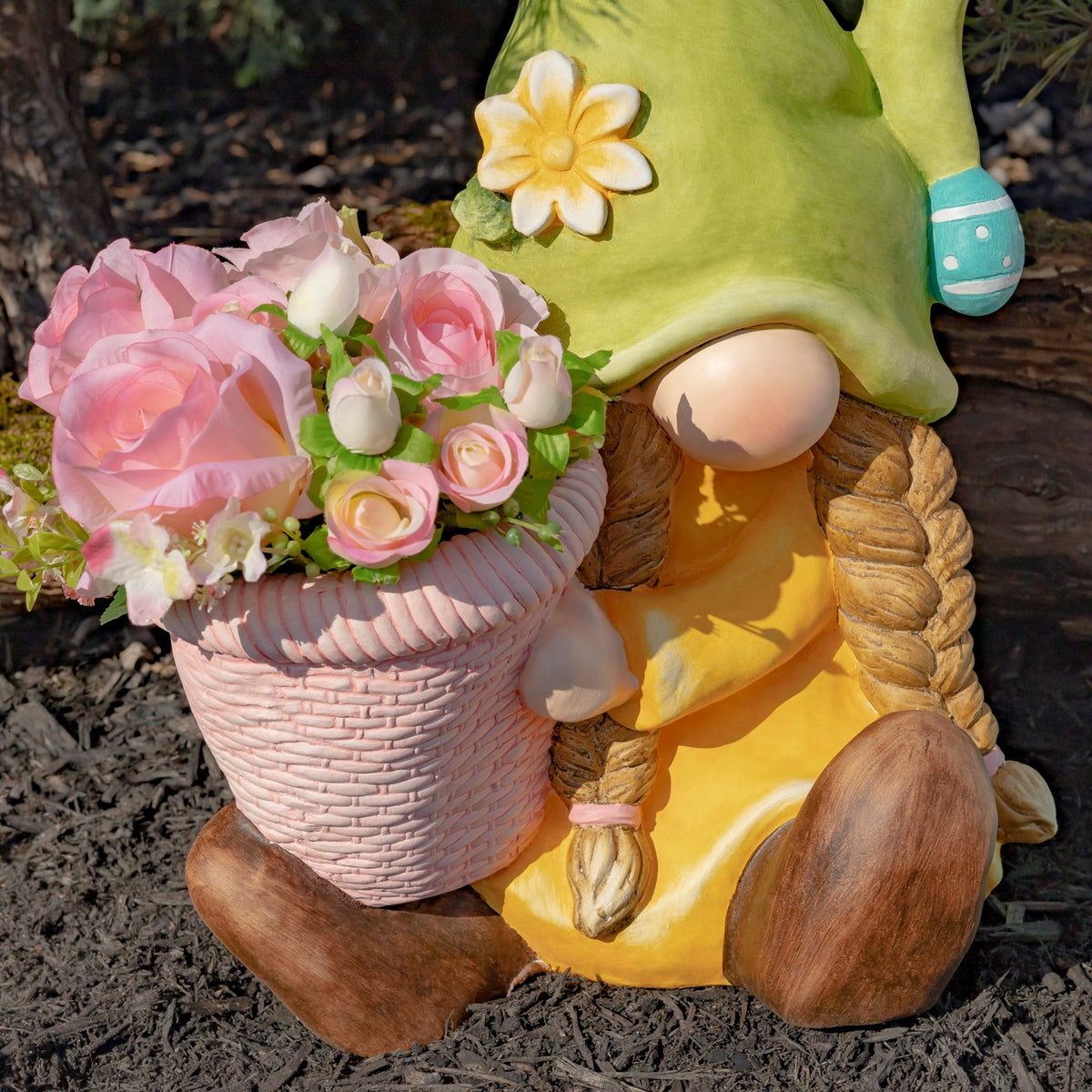 A green-hatted gnome holds a pink woven-look planter filled with pink and white flowers.