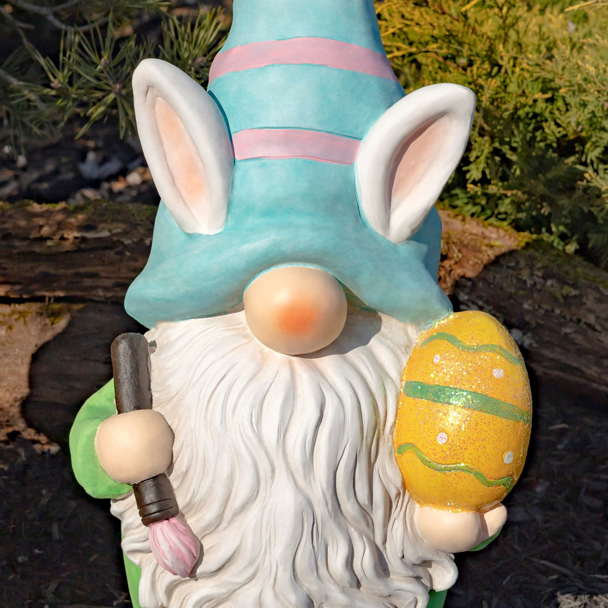 Close view of white-bearded gnome in a turquoise striped hat holding an egg and paintbrush