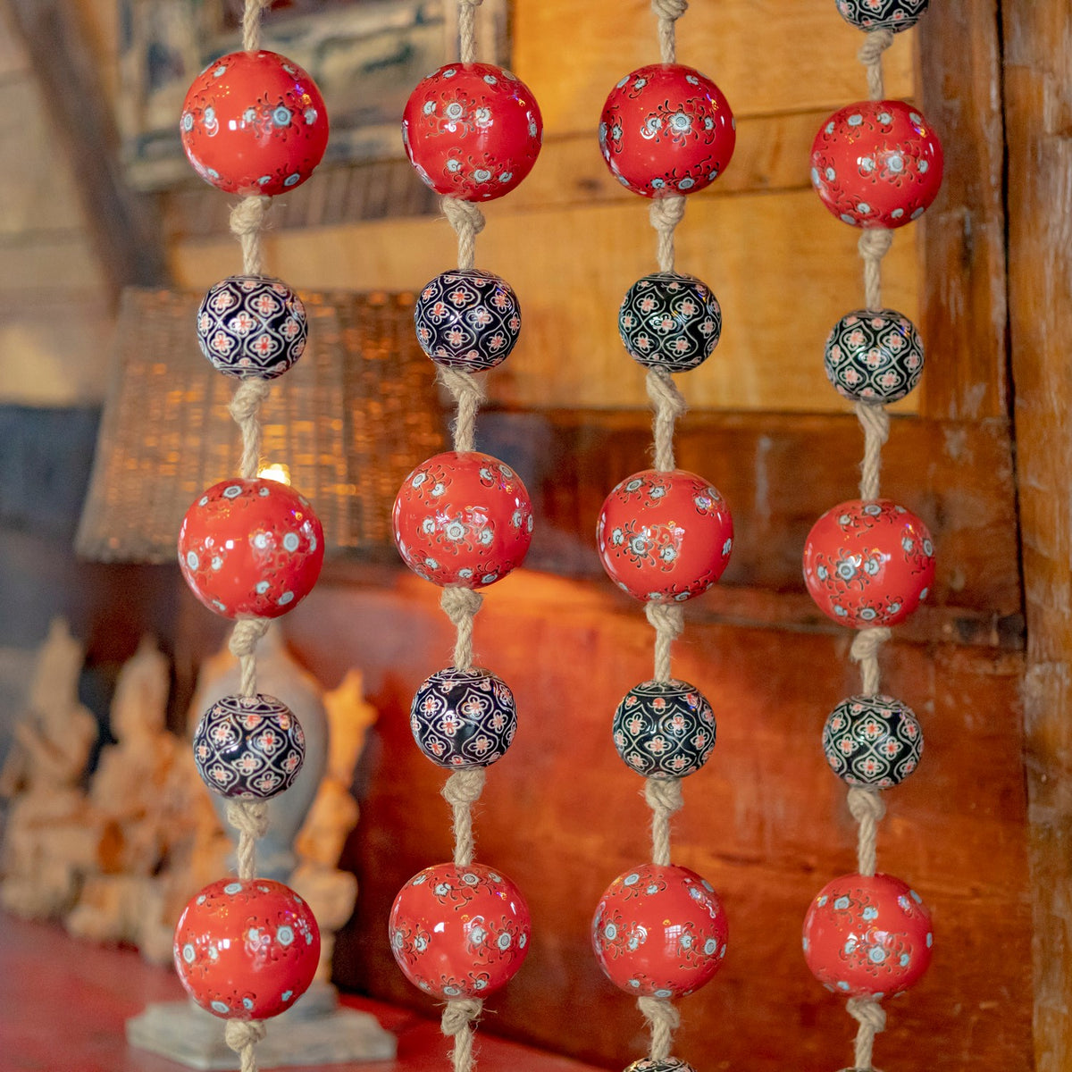 Close-up of red and dark patterned porcelain balls tied along coarse rope strands.