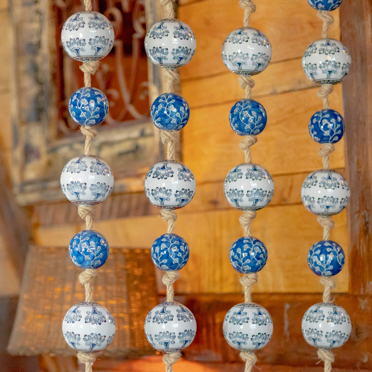 Close view of blue and white floral-patterned balls tied along coarse rope strands.