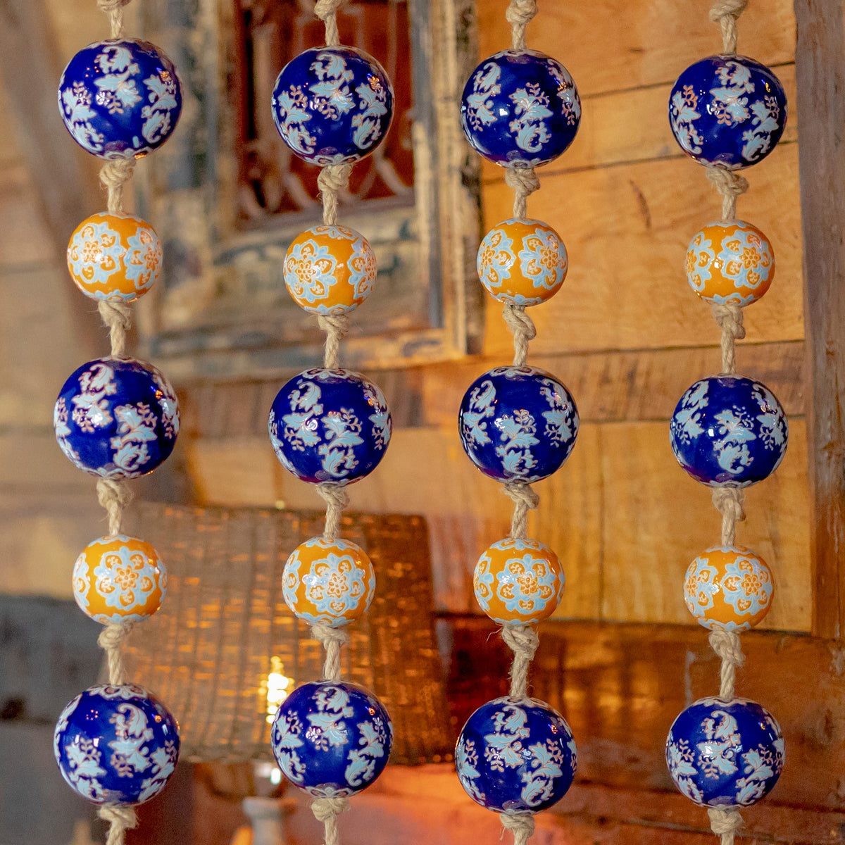Close view of alternating blue and orange floral-patterned balls tied along four twine strands.