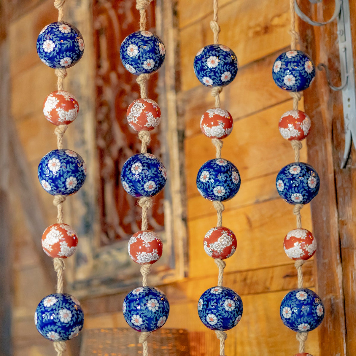 Close-up of alternating blue and burnt-orange floral balls threaded along coarse natural-colored cord.