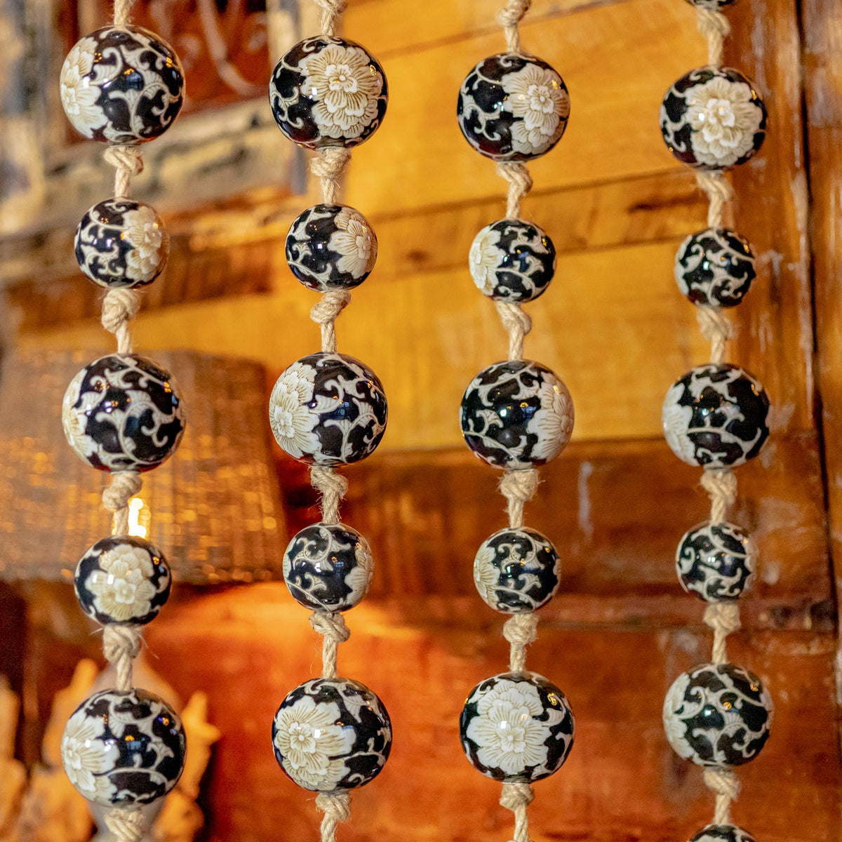 Close-up of floral and swirling patterns on porcelain balls tied along four rope strands.
