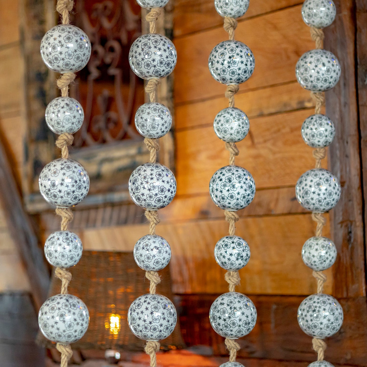 Close view of patterned porcelain balls tied along four twisted jute cords.