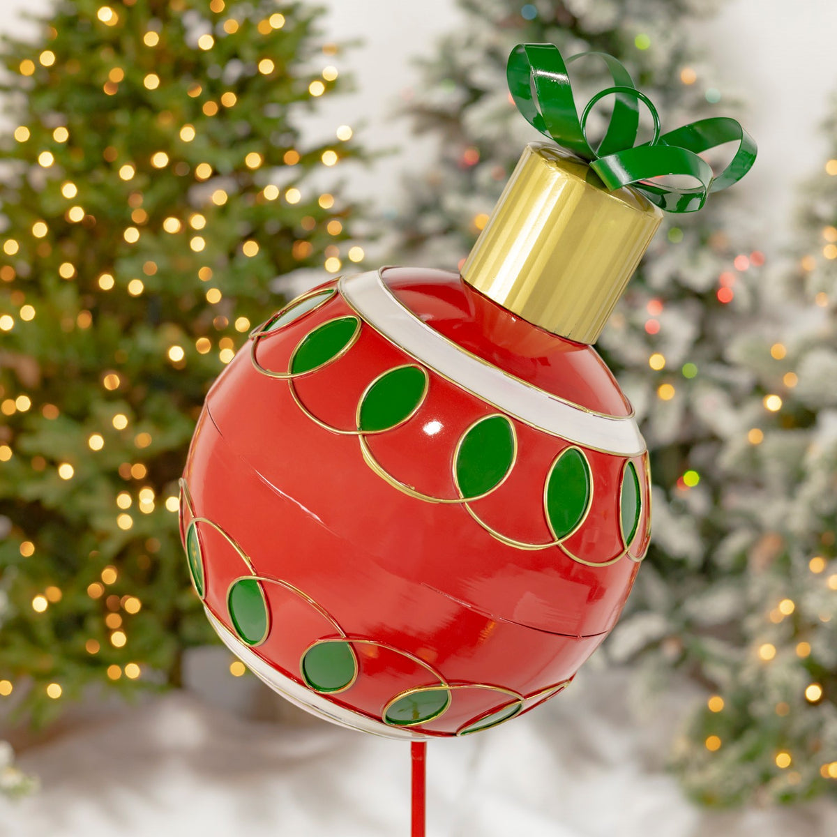 Close view of the red ornament with green oval accents, gold trim, a gold cap and green bow.