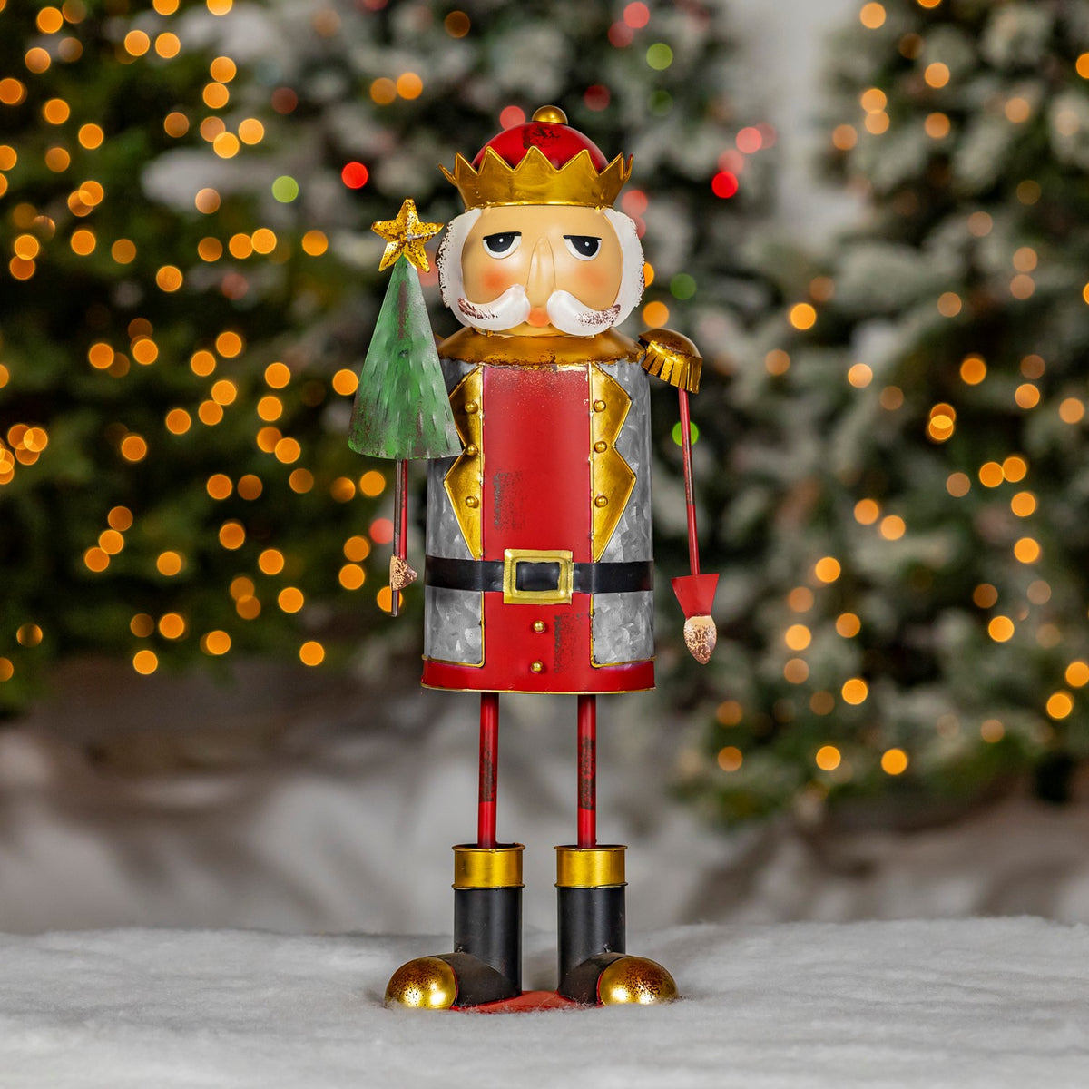 Full view of a red and silver nutcracker figurine beside a green Christmas tree