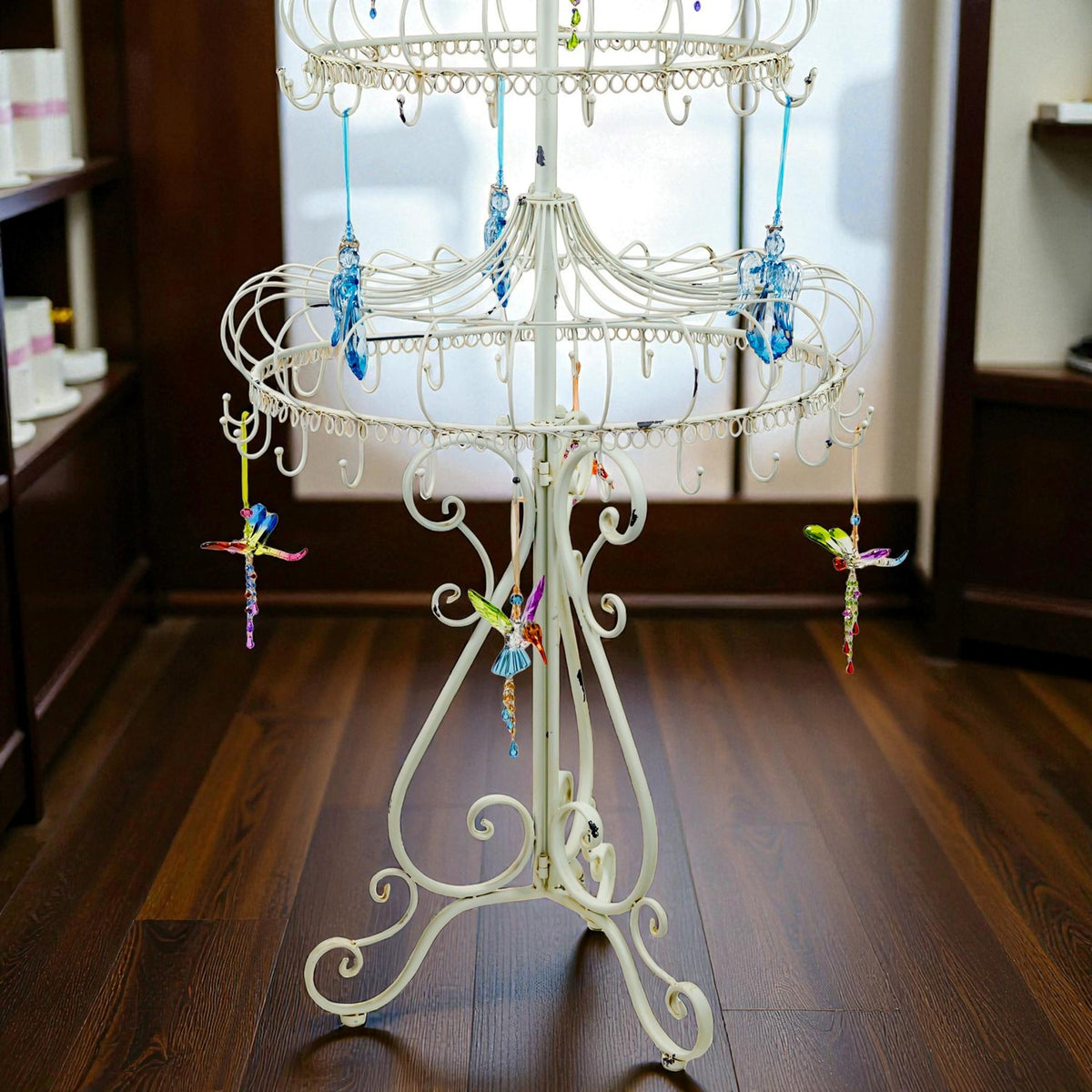 Close view of the stand’s curled metal base, lower tier, hanging hooks, and dangling ornaments.